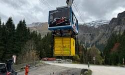 À la station aval, la nacelle prend en charge un conteneur pour le transport de charges. L'opérateur commande l'opération par radiocommande.