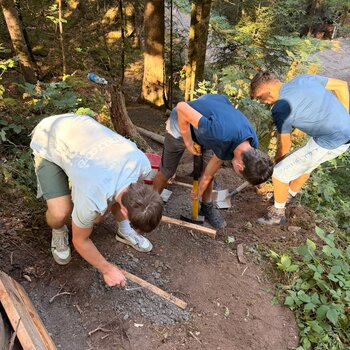 Eine Gruppe arbeitet an einer Treppe für den Wanderweg.