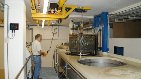 Kransystem hebt Metallbehälter aus Becken