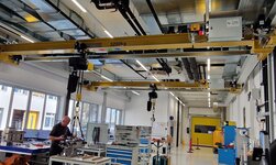 Maschinenbauteile werden mit dem Laufkran auf die Werkbank gehoben
